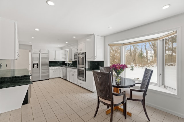 kitchen featuring white cabinetry, appliances with stainless steel finishes, light tile patterned floors, and backsplash