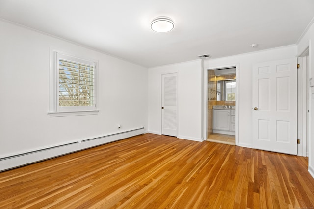 unfurnished bedroom with a baseboard heating unit, ensuite bath, ornamental molding, and light hardwood / wood-style floors