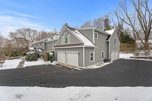 view of snow covered exterior featuring a garage and central AC unit