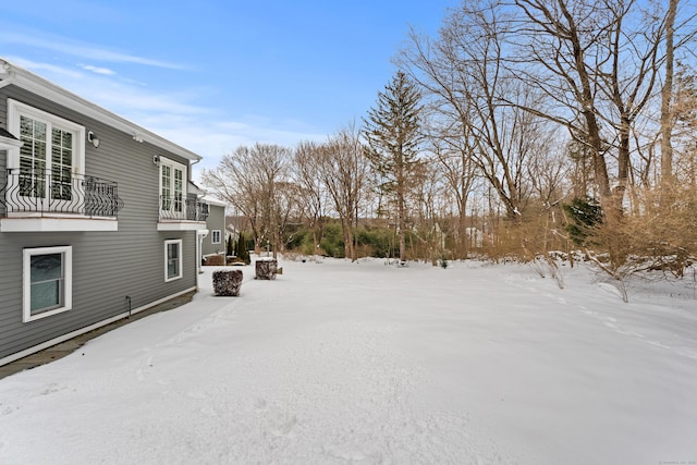 yard covered in snow featuring a balcony