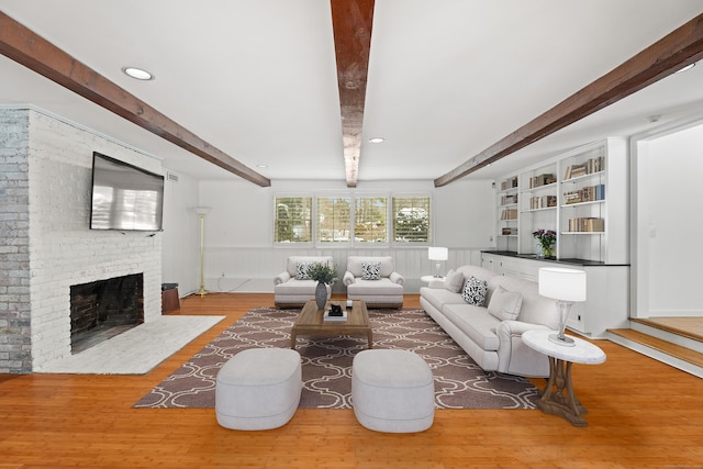 living room with hardwood / wood-style floors, beam ceiling, and a fireplace