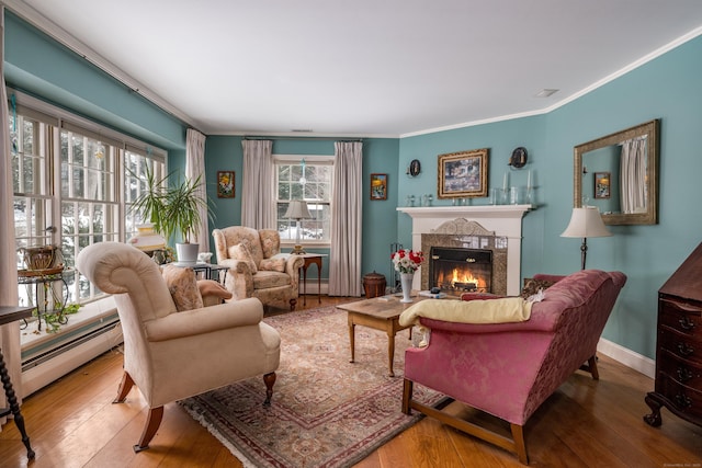 interior space with a warm lit fireplace, ornamental molding, hardwood / wood-style flooring, and baseboards