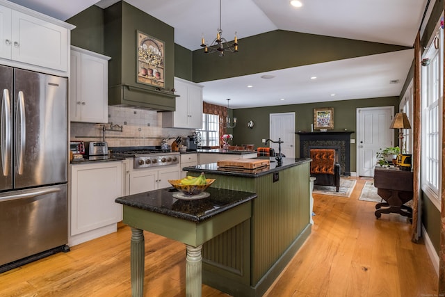 kitchen featuring white cabinets, stainless steel appliances, light wood-style flooring, and an inviting chandelier