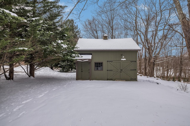 snow covered structure with an outbuilding