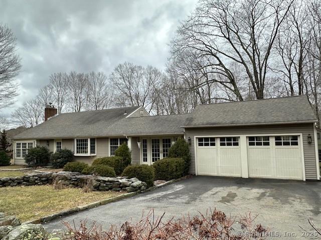 ranch-style home with driveway, a garage, and a chimney