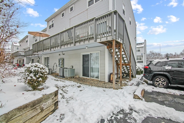 snow covered back of property with central AC