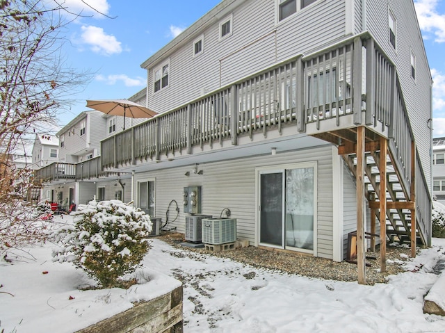 snow covered rear of property with stairs, central AC, and a wooden deck