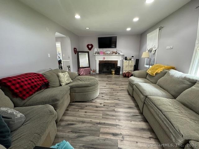 living room featuring a brick fireplace and light wood-type flooring