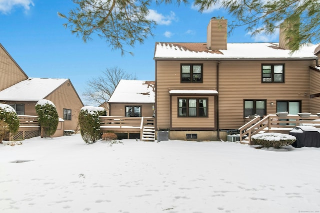 snow covered property with a wooden deck and central AC unit