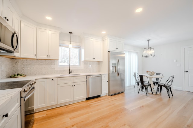 kitchen featuring white cabinetry, pendant lighting, stainless steel appliances, and a sink