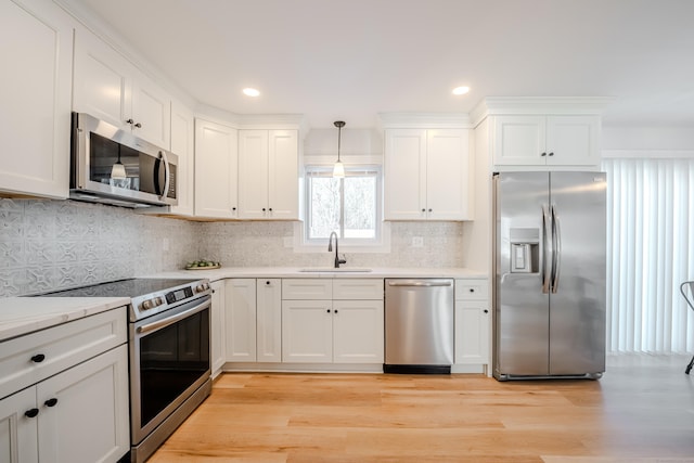 kitchen featuring white cabinets, pendant lighting, stainless steel appliances, and a sink