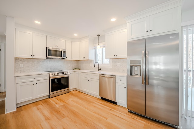 kitchen featuring appliances with stainless steel finishes, light countertops, hanging light fixtures, and a sink