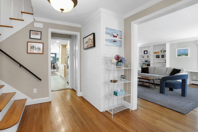 hallway featuring baseboards, crown molding, stairway, and hardwood / wood-style floors