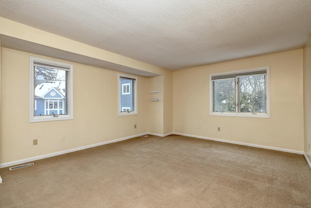 unfurnished room with a wealth of natural light, visible vents, light carpet, and baseboards