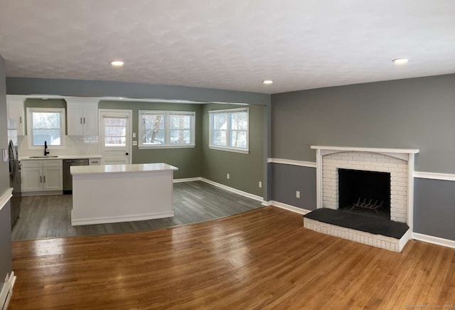 kitchen with white cabinetry, black dishwasher, sink, and dark hardwood / wood-style floors