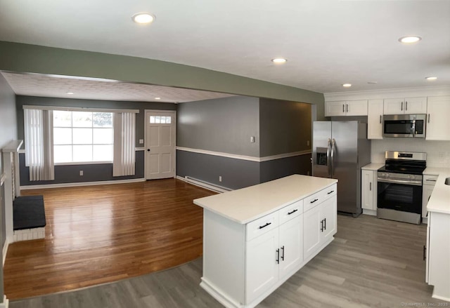 kitchen with white cabinetry, a center island, baseboard heating, stainless steel appliances, and light wood-type flooring