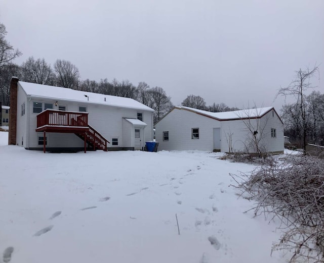 snow covered rear of property with a wooden deck