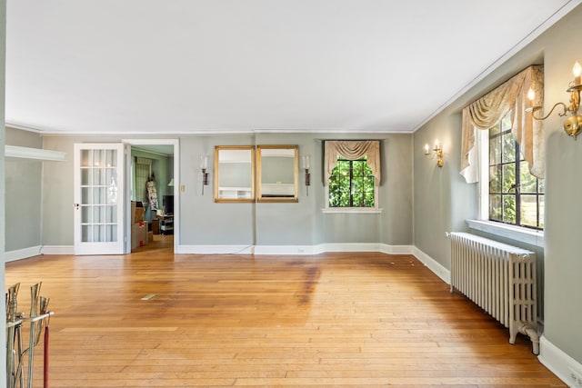 empty room featuring crown molding, radiator heating unit, and light hardwood / wood-style floors