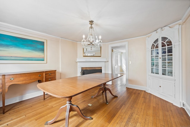 dining area featuring an inviting chandelier, a fireplace, and light wood-type flooring