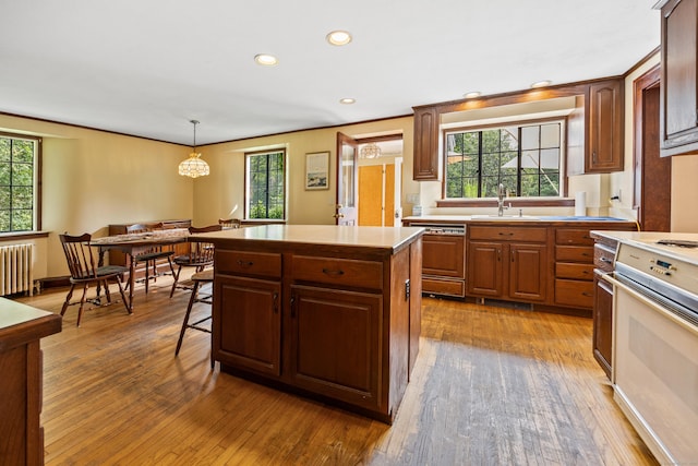 kitchen with pendant lighting, sink, radiator, paneled dishwasher, and a kitchen island