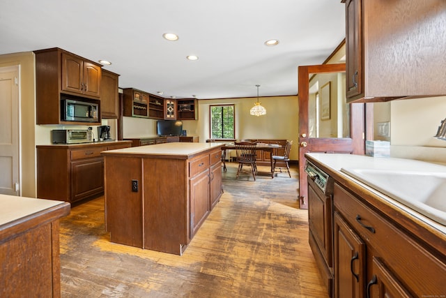 kitchen featuring dark wood-type flooring, dishwasher, a kitchen island, built in microwave, and decorative light fixtures