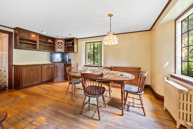 dining room with hardwood / wood-style flooring, a healthy amount of sunlight, radiator, and crown molding