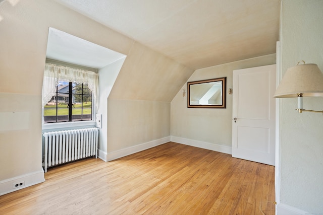 additional living space with lofted ceiling, radiator heating unit, and light hardwood / wood-style floors