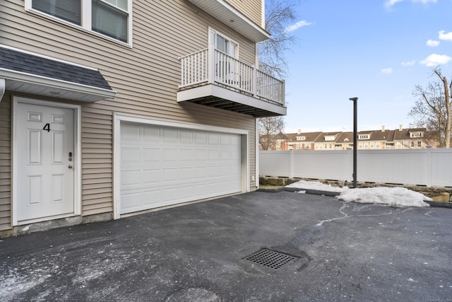 garage featuring aphalt driveway, a residential view, and fence