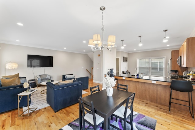 dining space featuring light wood-type flooring, ornamental molding, a notable chandelier, and recessed lighting