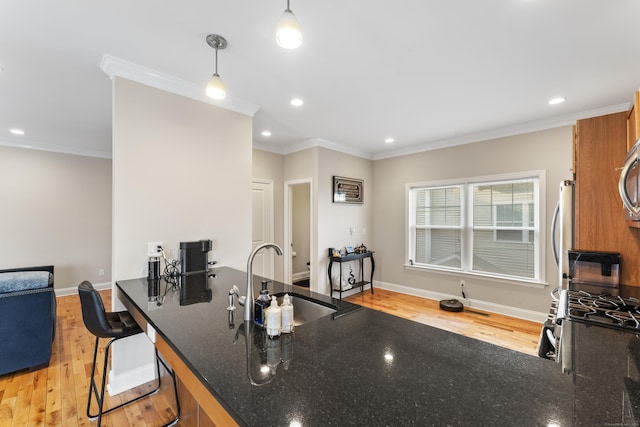 kitchen with crown molding, light wood-type flooring, and a sink