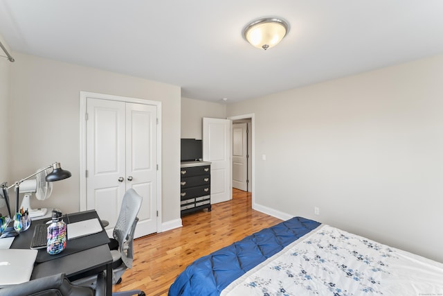 bedroom featuring light wood finished floors, baseboards, and a closet