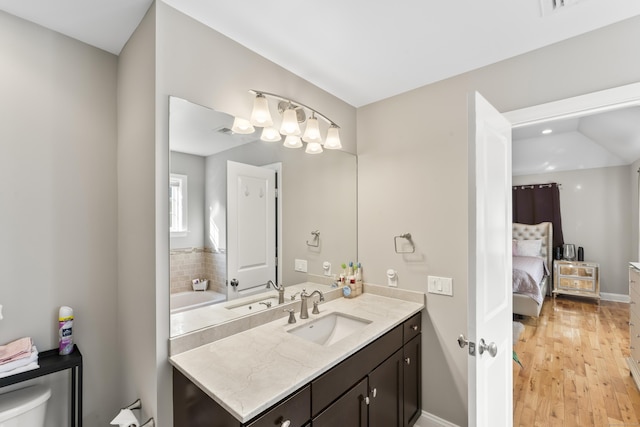 bathroom with visible vents, connected bathroom, vanity, wood finished floors, and baseboards