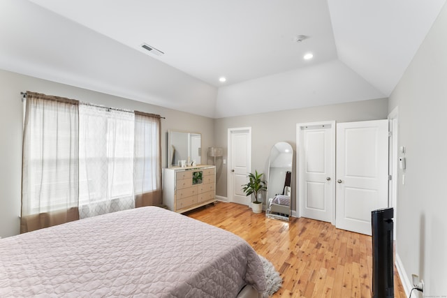 bedroom with light wood-type flooring, lofted ceiling, visible vents, and baseboards