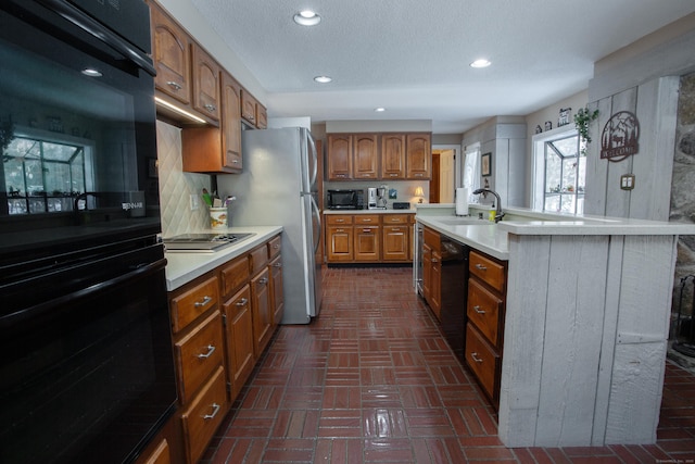 kitchen with a center island with sink, sink, black appliances, and a textured ceiling