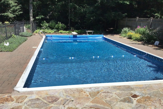 view of swimming pool with a diving board