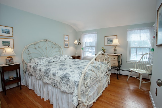 bedroom featuring multiple windows, hardwood / wood-style flooring, lofted ceiling, and baseboard heating