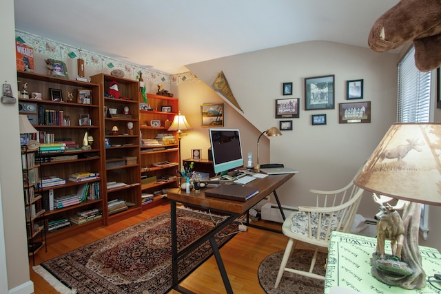 office space featuring lofted ceiling, hardwood / wood-style floors, and baseboard heating