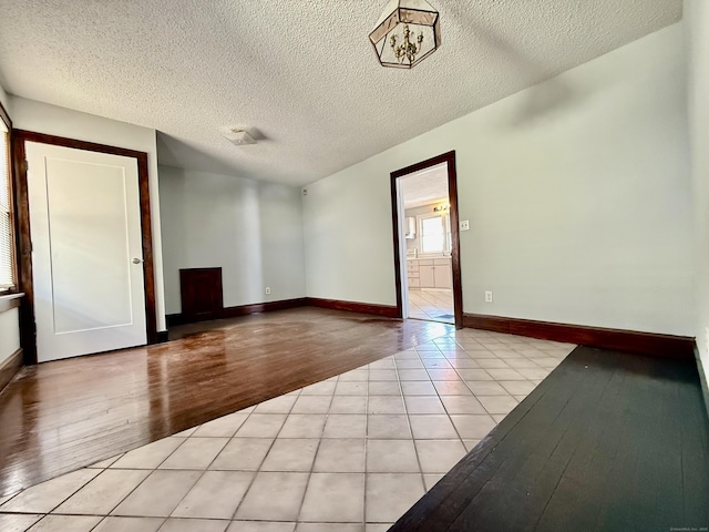 unfurnished room with a textured ceiling and light wood-type flooring