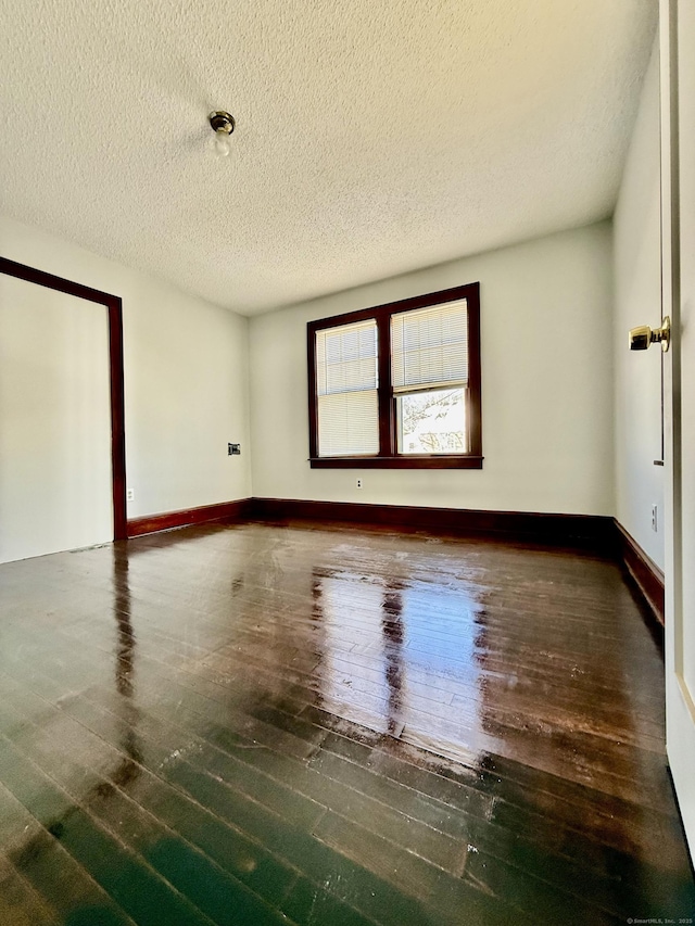 empty room featuring dark wood-type flooring and a textured ceiling