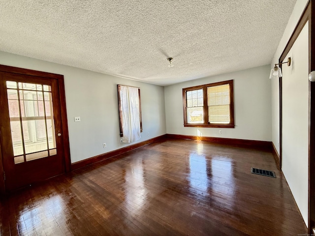 empty room with a barn door, dark hardwood / wood-style floors, and a textured ceiling