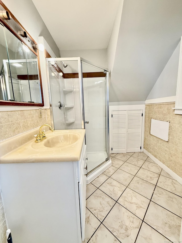 bathroom with a shower with door, vanity, lofted ceiling, and tile patterned floors