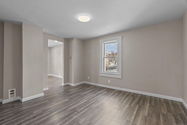 unfurnished room with dark wood-style flooring, visible vents, and baseboards