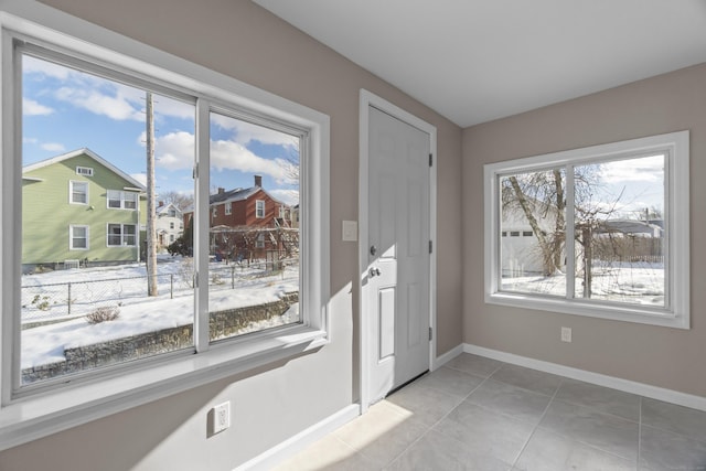 doorway to outside featuring a residential view, baseboards, and light tile patterned floors