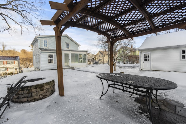 snow covered patio with an outdoor fire pit, a sunroom, and a pergola