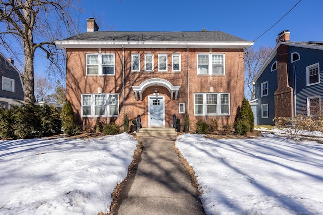 view of front of property with a chimney and brick siding