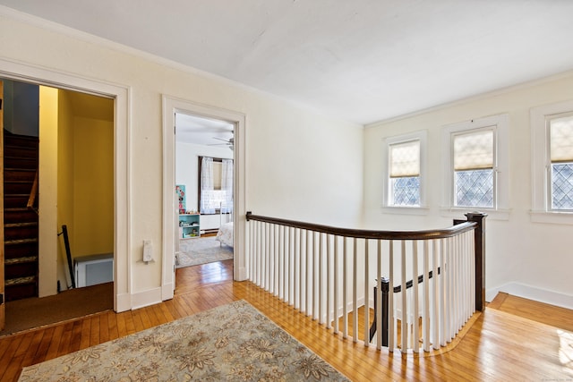 hallway with ornamental molding, stairs, baseboards, and wood finished floors