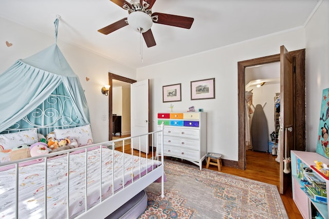 bedroom featuring wood finished floors, a ceiling fan, and crown molding