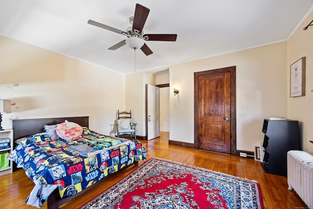 bedroom with baseboards, wood finished floors, a ceiling fan, and radiator