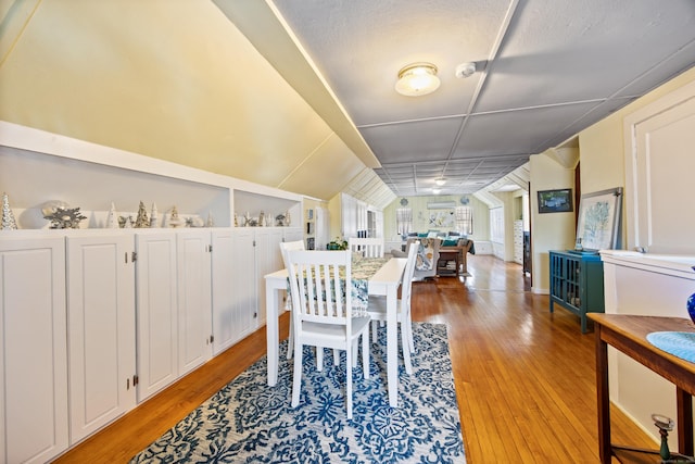 dining area with vaulted ceiling and light wood-type flooring