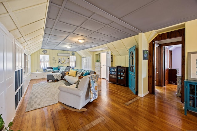 living room with vaulted ceiling, a wall unit AC, coffered ceiling, and wood finished floors